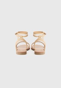 Brune sandaler med to ankelstropper, flatt hæl og et minimalistisk design. Læderoverdel med en glat tekstur og en naturlig sål.