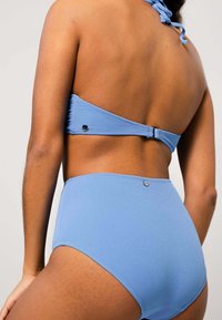 Ljusblå bikinisett med halterneck-top och högmidjade byxor med texturerad yta och metallaccenter på stängningarna.