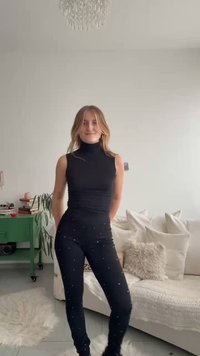 Čierny bezrukávový vrchný diel s rolákom v kombinácii s čiernymi legínami s roztrúsenými striebornými cvokmi. Hladká látka, priliehavý strih a mäkká štruktúra.