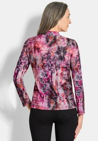 Langarm, meerkleurige blouse in tinten roze en paars met abstracte bloemen- en cirkelpatronen. Gladde stof met een fitted vorm.