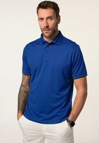 Modrá polo košile z hladkého, lehkého materiálu. Má límeček, zapínání na tři knoflíky a kontrastní černé akcenty na rukávech.