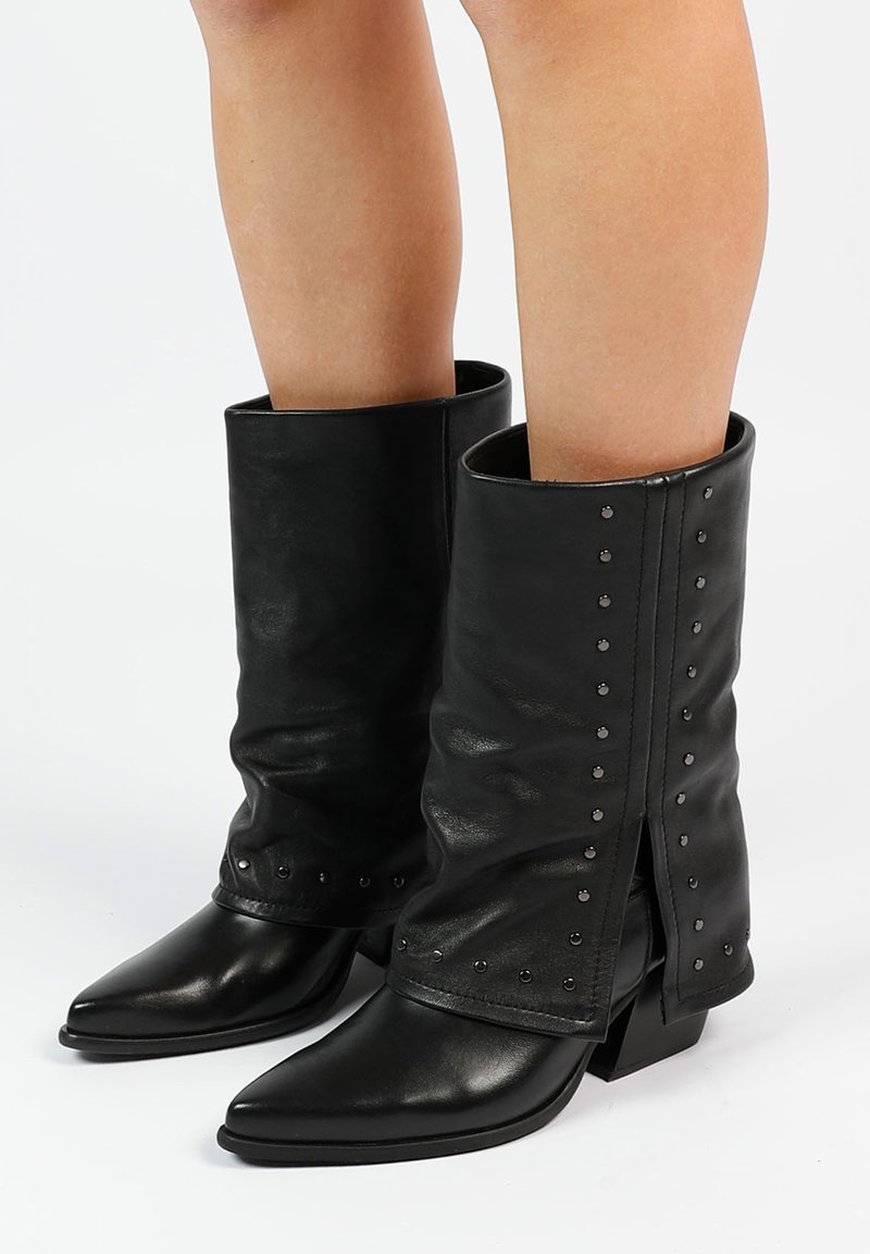 Bottines noires en cuir avec un dessus flou, bout pointu et clous décoratifs le long des coutures. Talons blocs pour plus de stabilité.