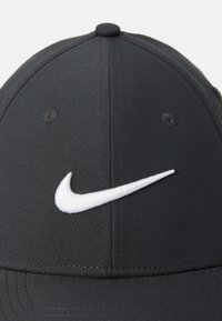 Sort baseball cap med et hvidt Nike swoosh-logo broderet på frontpanelet.