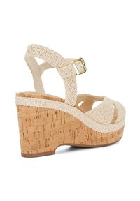 Beige wedge sandals with a cork platform, textured fabric straps, and a gold buckle accent. Crossed front straps enhance design.