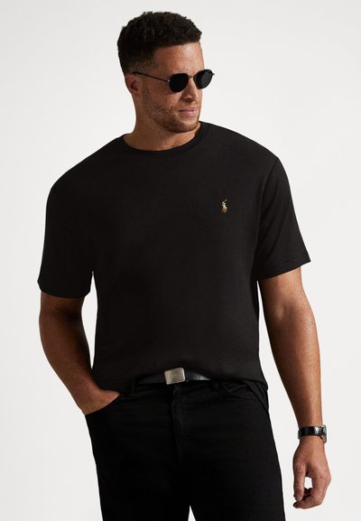 Svart bomulls-t-shirt med korta ärmar och rund halsringning. Har en liten broderad logotyp på vänster bröst. Kombinerad med svarta byxor.