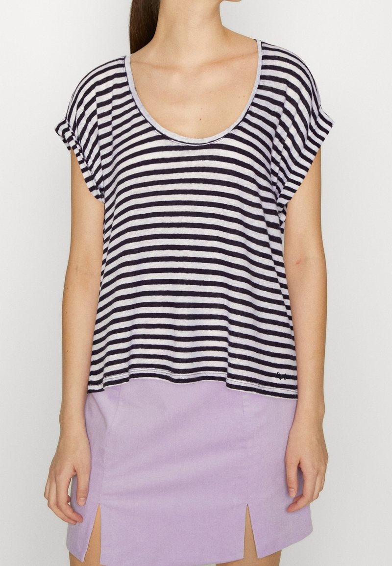 Pruhované tričko s krátkým rukávem v námořnické modři a bílé, s kulatým výstřihem a volným střihem, v kombinaci s lehkou levandulovou sukní s rozparky.