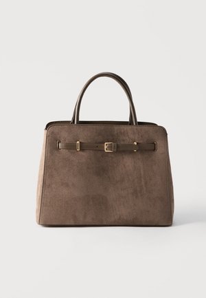 Bruine suède handtas met twee handvatten en een decoratieve leren band met gouden gesp aan de voorkant, tegen een effen achtergrond.
