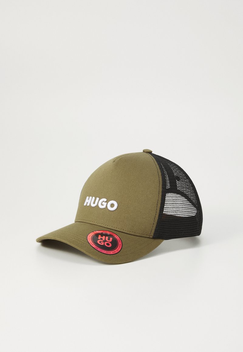Olivgrüner Hut mit einer abgerundeten Spitze, weißem "HUGO"-Logo auf der Vorderseite, schwarzen Netzseiten und einem runden roten Etikett an der Rückseite.
