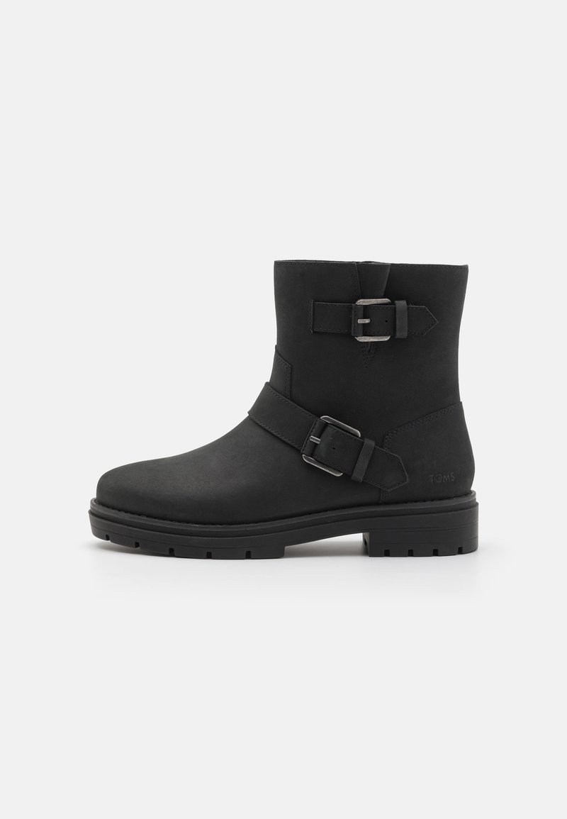 Ankle boot preta feita de couro mate com dois detalhes de fivela. Apresenta um bico arredondado e uma sola robusta para tração.