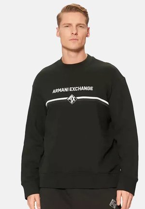 Zwarte sweatshirt van zachte stof met een ronde hals, lange mouwen en een wit logo en streep over de borst.