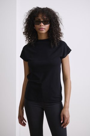 Black short-sleeve top with a high neckline, paired with black fitted jeans. The fabric appears smooth with a subtle texture.