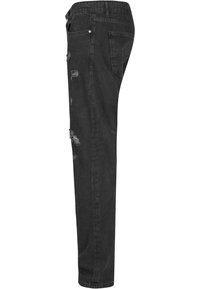 Mustat denim-farkut, joissa on kapea leikkaus, kuluneita yksityiskohtia reiden ja polven kohdalla sekä klassinen viiden taskun muotoilu.