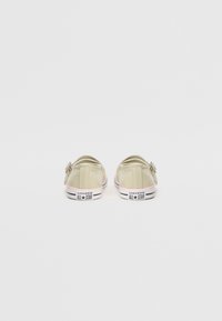 Chaussures en toile vert clair avec un talon arrondi, dotées d'une semelle en caoutchouc blanche et d'accents roses, affichant le logo « Converse All Star ».