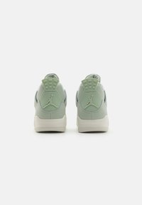 Jasnozielone sneakersy o gładkiej fakturze, z kontrastującymi ciemniejszymi akcentami oraz wyraźnym logo na pięcie. Okrągły kształt z wyściełanym kołnierzem.