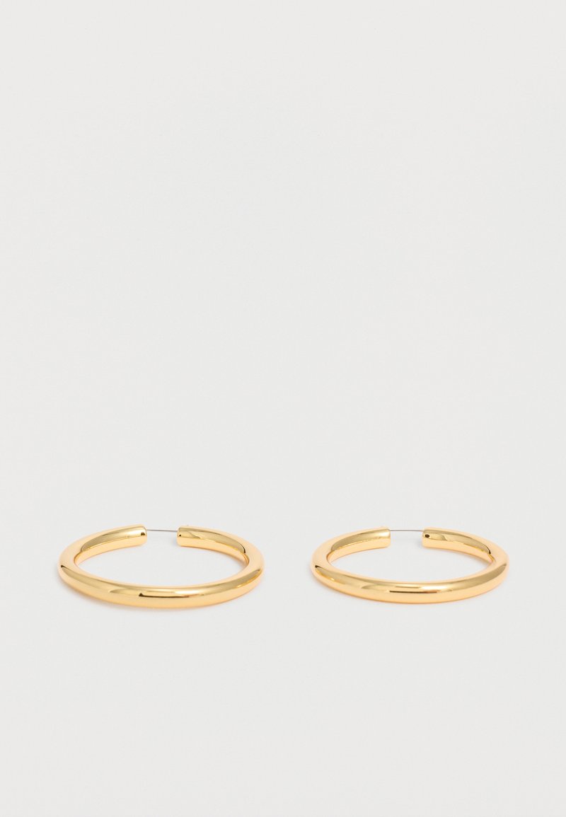 Ζευγάρι λαμπερά χρυσά κρίκοι με λεπτές αγκράφες σύρματος σε απλό λευκό φόντο.