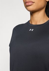 Σκούρο γκρι αθλητικό t-shirt με στρογγυλή λαιμόκοψη και κοντά μανίκια. Διαθέτει μικρό λευκό λογότυπο Under Armour στο στήθος. Λεπτή υφή.