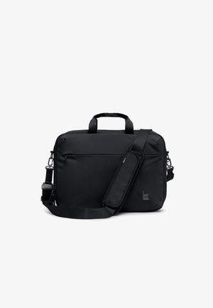 Czarna prostokątna torba na ramię z uchwytami, regulowanym wyściełanym paskiem, przednią kieszenią na zamek i małym logo "GOT BAG." na dole po prawej stronie.