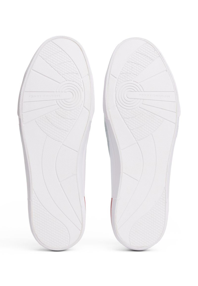 Semelles de chaussure en caoutchouc blanc avec un motif de traction texturé, comportant un design circulaire et un logo estampé sur une semelle.