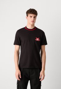 Black cotton t-shirt with red ribbed collar, featuring a bold embroidered graphic on the chest, short sleeves, and a relaxed fit.
