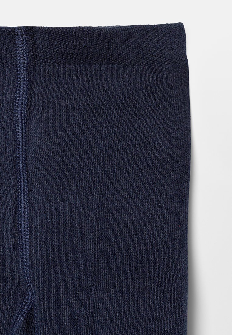 Close-up van marineblauwe gebreide stof met zichtbare ribbels en een verticale naad voor de rand van een sok of mouw.