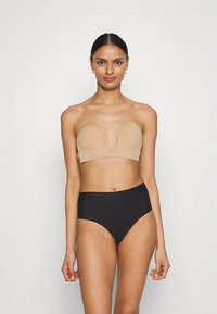 Bézs színű pánt nélküli melltartó formázott kosarakkal, mély dekoltázzsal, magas derekú fekete alsóval párosítva. Sima textúra és varrás nélküli kivitel.