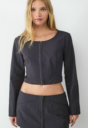 Zwarte cropped jacket met verticale streepjes, ronde halslijn, lange mouwen en een ritssluiting aan de voorkant. G combineerd met een bijpassende hoge taille rok.