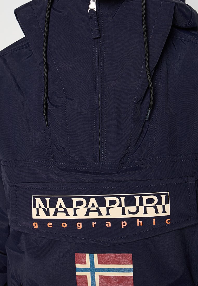 Veste polaire bleu marine avec un col montant, capuche réglable avec cordon, poche avant et logo "NAPAPIJRI geographic" avec un patch ressemblant au drapeau de la Norvège.