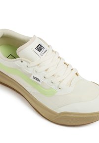 White canvas sneaker with a green side stripe and cream accents. Features a textured upper, rounded toe, and rubber sole with grip pattern.