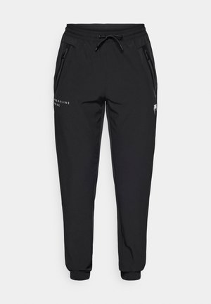 Juodos sportinės kelnės iš lengvos medžiagos, su elastinga juosmens juosta ir raišteliu, šoninėmis kišenėmis su užtrauktukais ir užsegamais apačiais.