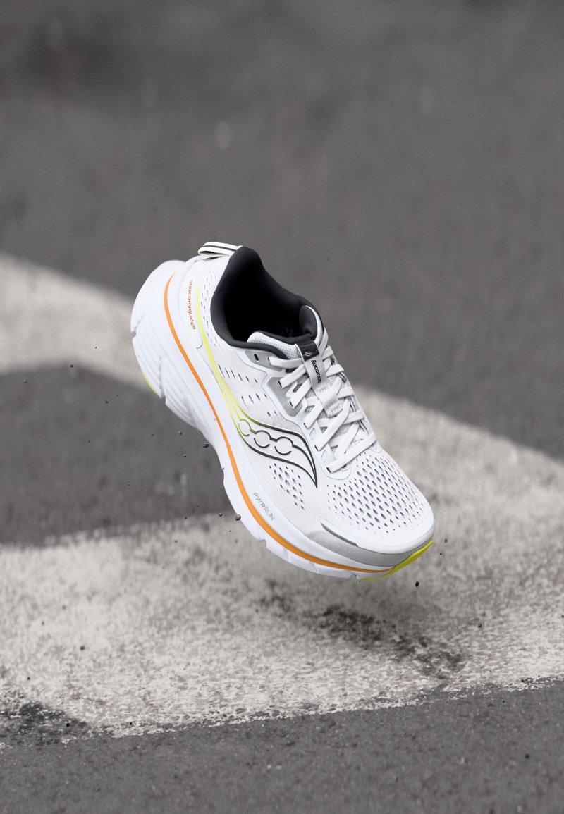 Weißer Laufschuh mit einem Obermaterial aus Mesh, schwarzen Akzenten und leuchtenden gelben und orangefarbenen Details. Verfügt über eine gepolsterte Sohle und Schnürverschluss.