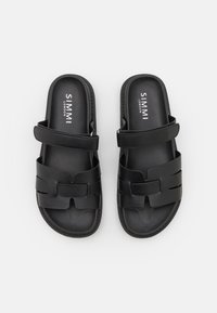 Svarta slidesandaler med en slät syntetisk ovandel som har en bred remdesign och logodetalj, placerade på en strukturerad sula för bättre grepp.