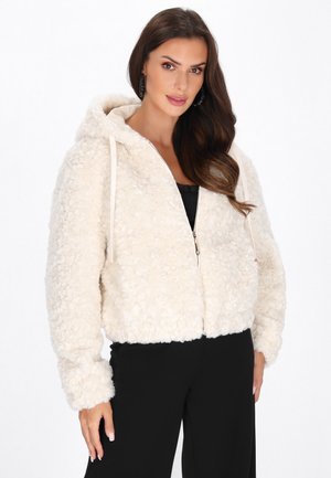 Giacca in pile morbido color crema con cappuccio, zipper frontale e lacci; presenta maniche lunghe e un design corto.