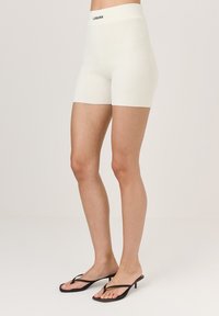Prążkowane, kremowe szorty z wysokim pasem oznaczone "LAMANA". Zaprojektowane, aby dopasować się ciasno, podkreślające gładką teksturę.