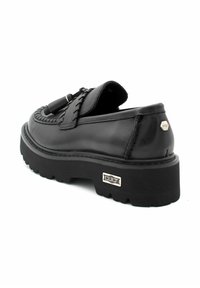 Chaussure en cuir noir avec un dessus texturé et des coutures proéminentes, dotée d'une semelle en caoutchouc épaisse et d'un petit accent en métal logo.