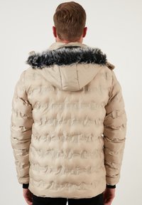Beige puffer jacket with horizontal baffle stitching, a detachable black faux fur hood trim, and elasticated cuffs. Smooth, glossy fabric finish.