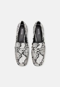 Mustvalged must-valge käärmeprindiga loaferid, millel on lame disain, volditav detail ja siledast materjalist sisepind. Tekstureeritud välimine materjal.
