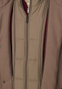 Veste en couches marron avec une doublure intérieure matelassée et rembourrée beige et une sous-couche bordeaux, avec un extérieur lisse et des fermetures éclair.