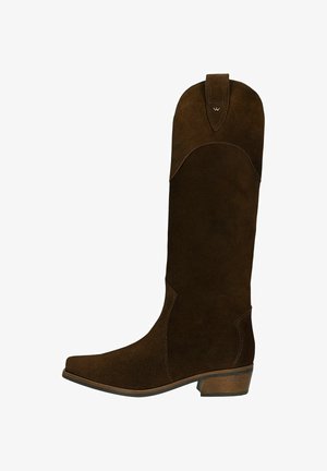 Brązowy zamszowy kozak sięgający kolan z szpiczastym noskiem i wygiętym szczytem. Posiada akcenty w postaci przeszyć oraz podwyższoną podeszwę dla wsparcia.