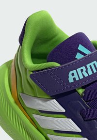 Green and purple athletic shoe featuring a textured upper, three white stripes, and a padded collar for comfort. Velcro strap included.