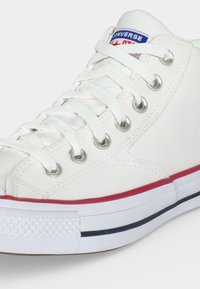 Άσπρο ψηλό αθλητικό παπούτσι Converse με λευκά κορδόνια, μεταλλικά κουμπώματα, μπλε και κόκκινο γείσο στη σόλα και το λογότυπο της μάρκας στη γλώσσα.