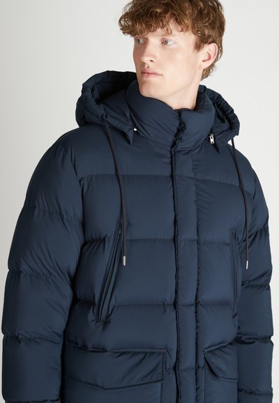 Giacca a piumino blu navy con cappuccio, caratterizzata da sezioni trapuntate, colletto alto, tasche con cerniera e cordini regolabili. Tessuto liscio.