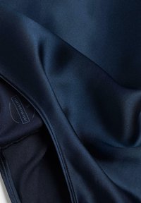 Marineblauwe sportstof met een gladde, glanzende textuur; toont stikseldetails en een label met 'S' voor maat.