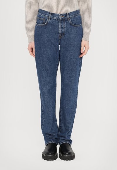 Light blue denim jeans with a straight cut, five-pocket design, and stitched detailing. Worn with black platform shoes.