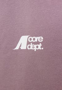 Tissu lilas clair avec le texte blanc "core dept." et une lettre "A" stylisée incorporée dans le design.