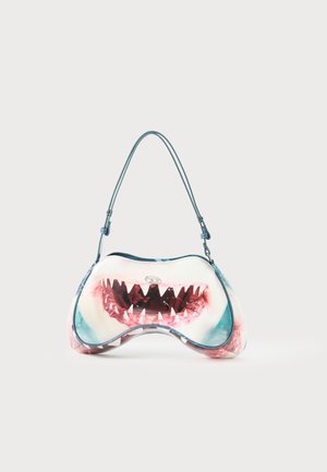 Handbag shaped like a shark’s open mouth with sharp teeth, featuring a blue strap and a clasp closure on a plain background.