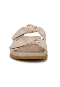 Sandali in pelle beige chiaro con cinturini annodati e soletta in suede morbido, dotati di una suola piatta e testurizzata per aderenza e comfort.