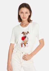 Witte katoenen T-shirt met een grafiek van een hond met rode accenten en tekst. Korte mouwen, losvallende pasvorm en een ronde halslijn.