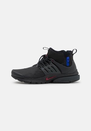 Chaussures de sport noires avec une tige haute, en mesh et synthétique, présentant des accents rouges et bleus, et un design de semelle rembourrée.