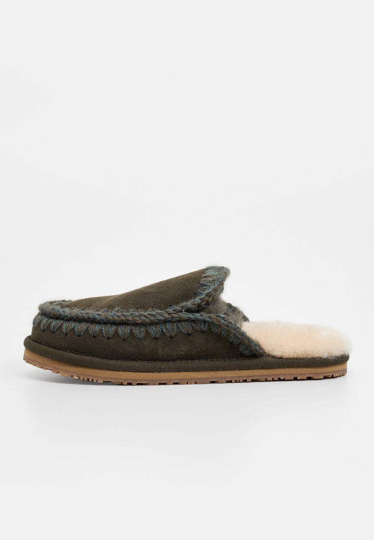 Groene suède slipper met een crèmekleurige nepbont lining, een gevlochten blauwe accent aan de rand en een rubberen zool voor grip.