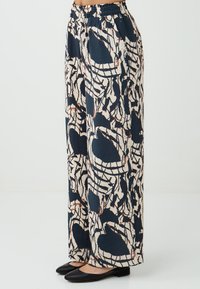 Wijd-gesneden broeken van marineblauwe en crèmekleurige stof, met abstracte patronen en een elastische tailleband. Effen textuur en casual stijl.